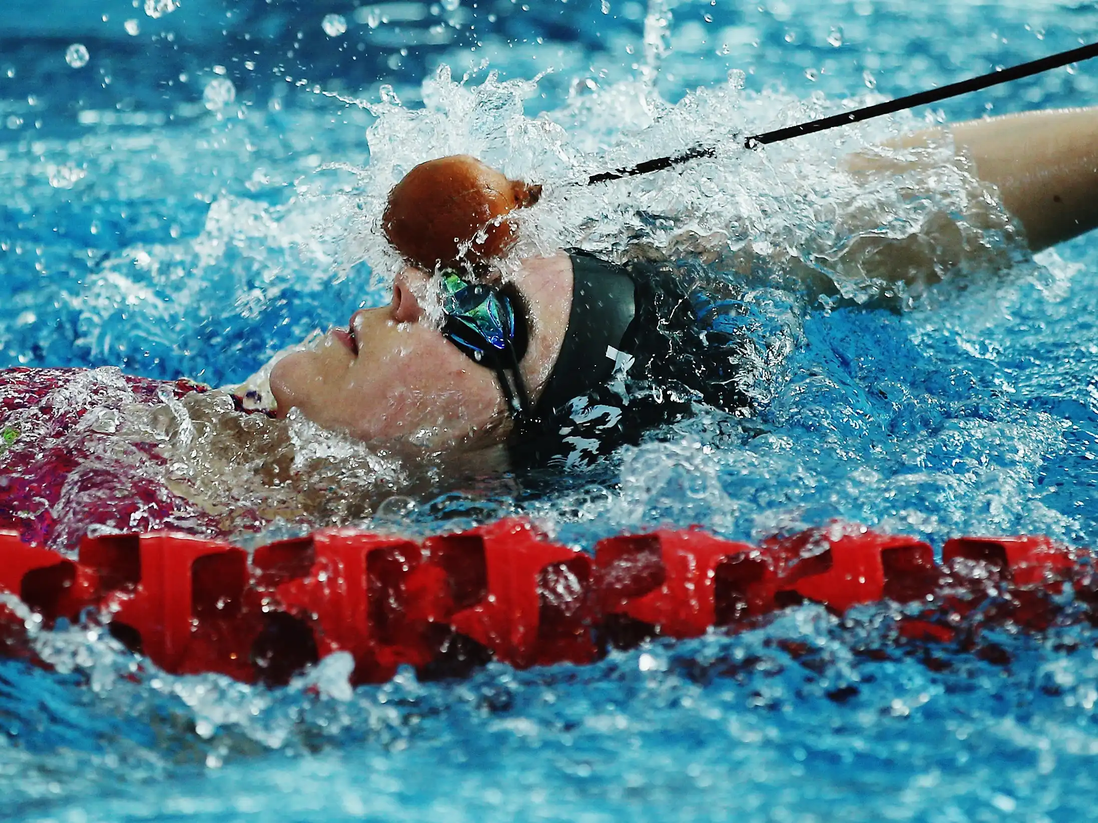 Paralympian #174 Amy Fisher receives a tap from a pole signalling her to make a turn at the end of the swimming pool lane.