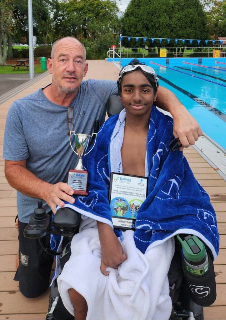Henk holds a trophy and a certificate next to Para swimmer Ashmit Danney.
