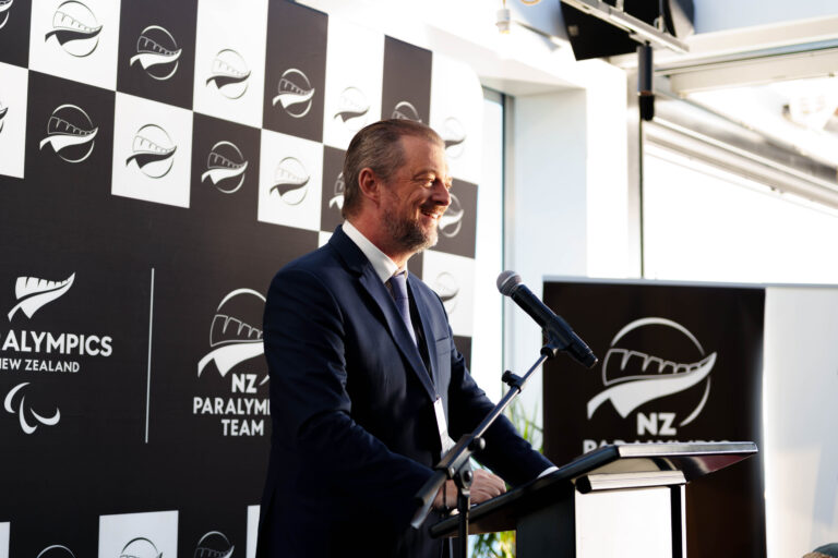 IPC President Andrew Parsons pictured in front of a lecturn with a Paralympics New Zealand backdrop