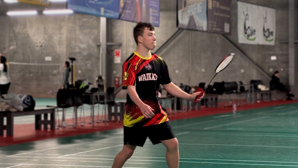 Andrew Fairweather competes in Para badminton wearing a Waikato tshirt.