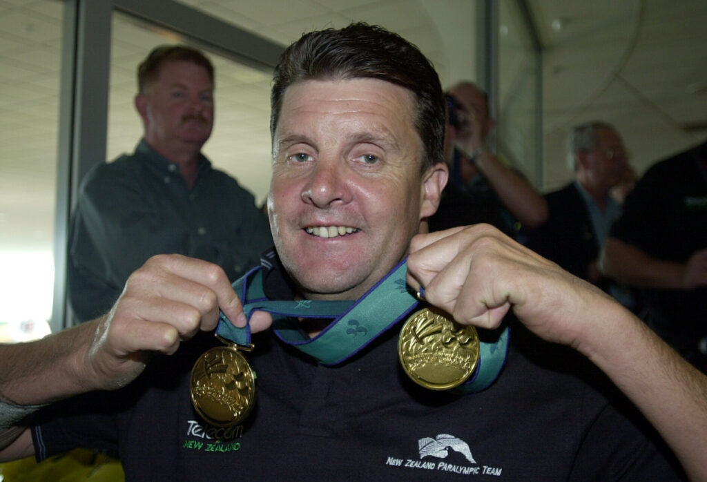 Dave MacCalman holds his two gold medals around his neck from the Sydney 2000 Paralympic Games.