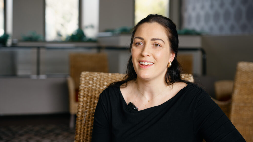 Dame Sophie Pascoe sits in a chair, smiling.