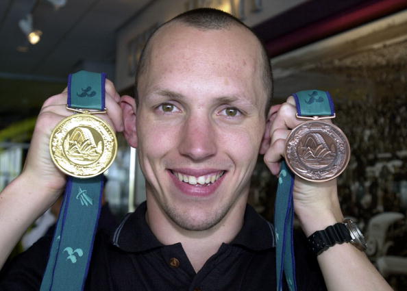 Dean Booth holds his gold and bronze medals from Sydney 2000.