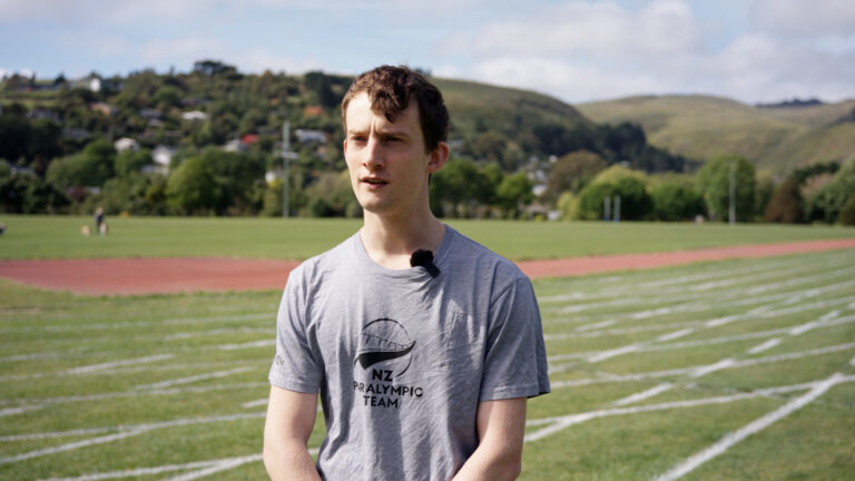 Will Stedman stands on a field with track lines painted behind him.