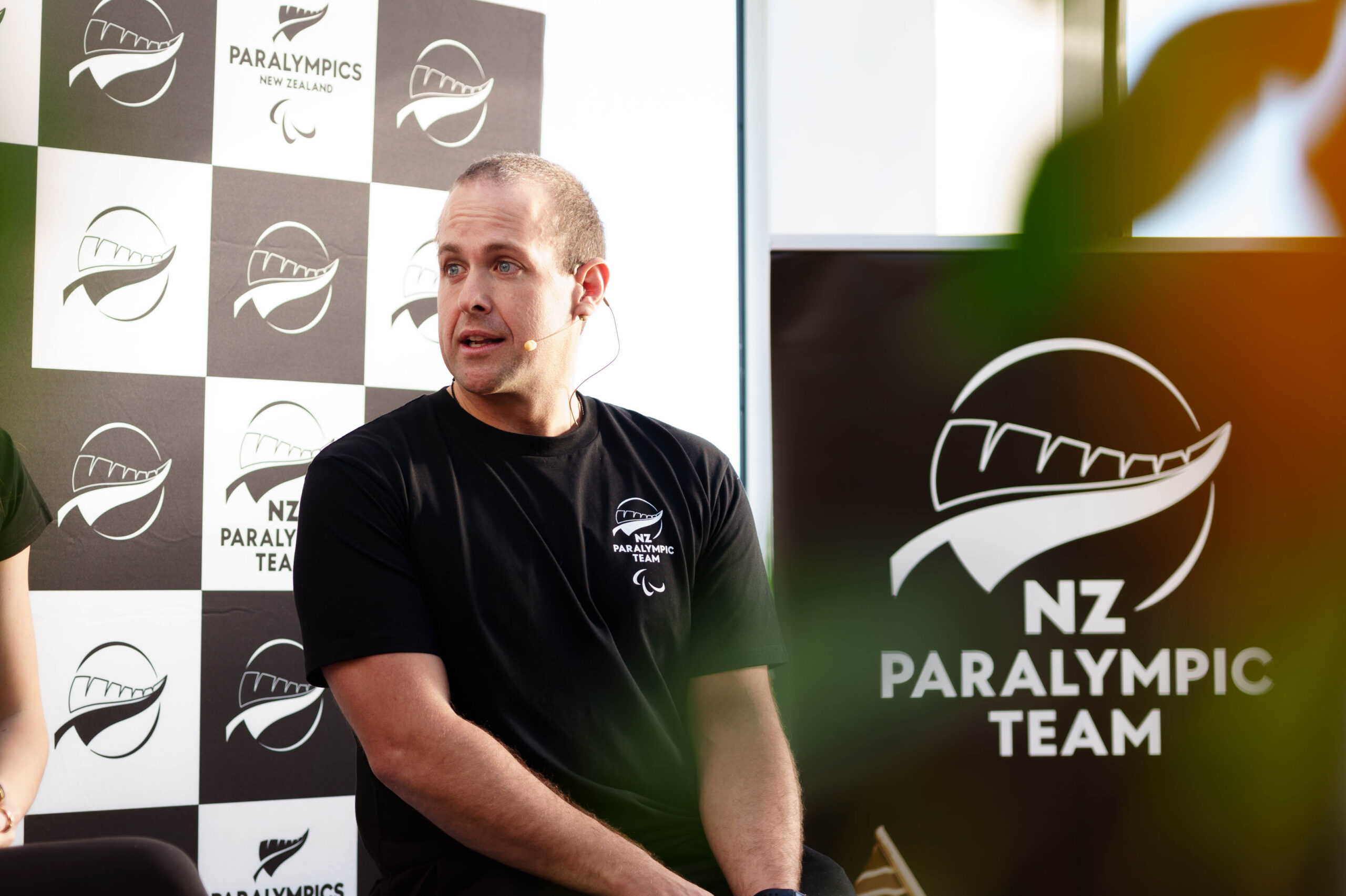 Adam Hall speaks on stage at a NZ Paralympic Team event.