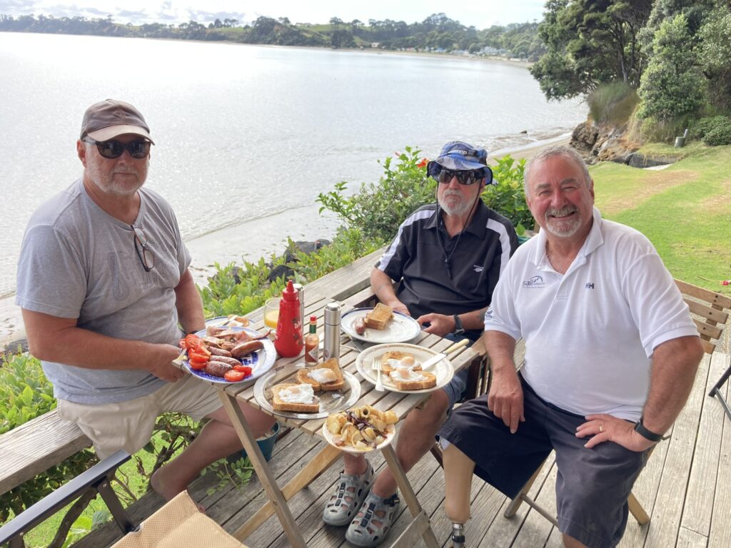 Chris and friends sit beside a lake.