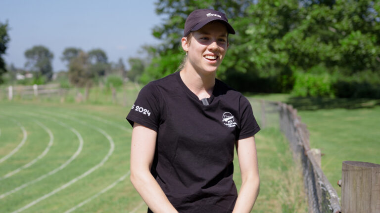 Danielle Aitchison stands on a field with an athletics track painted on the grass.