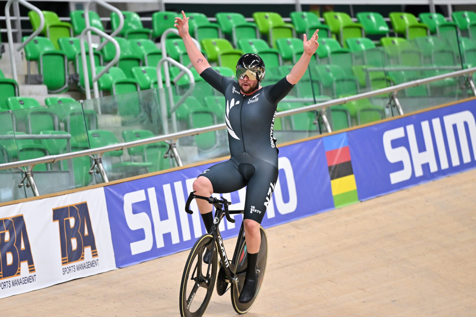Devon Briggs raises his hands in celebration on the velodrome after winning gold.