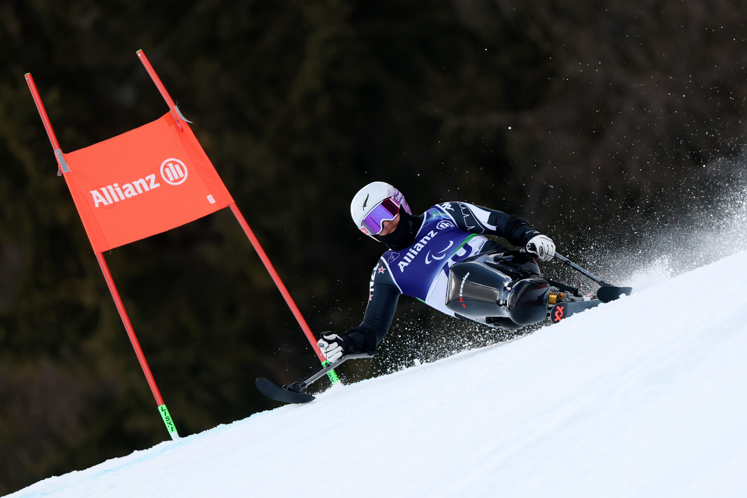 Corey Peters in the Men's giant slalom sitting at a diagonal angle rounding a red gate.