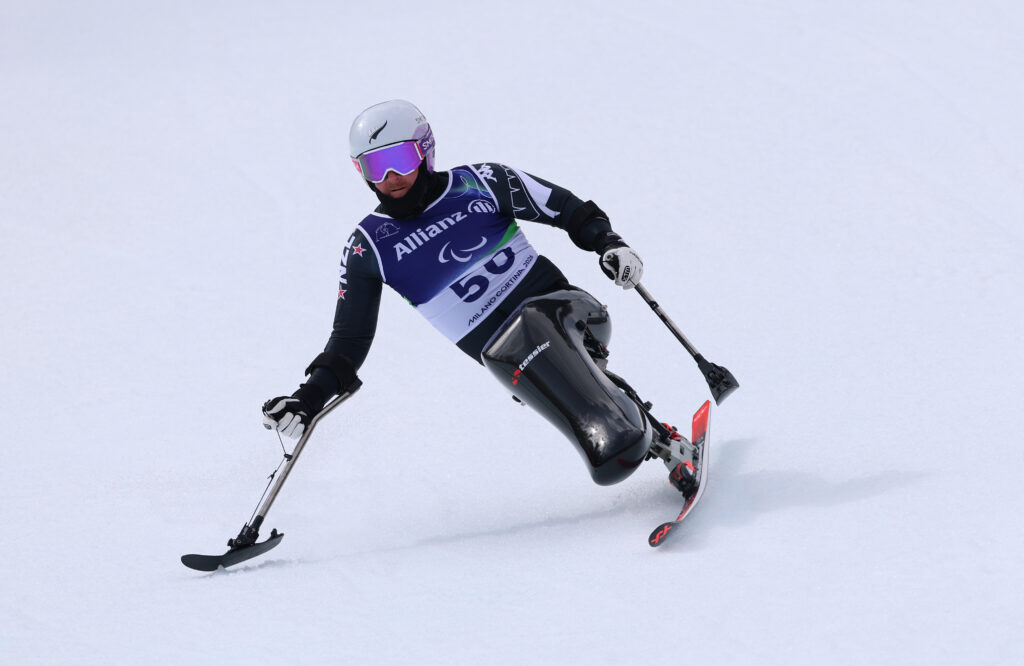 Sit skier Corey Peters in action in the Men's Super-G Sitting at Milano Cortina 2026. He is the middle of the image with a completely white background.