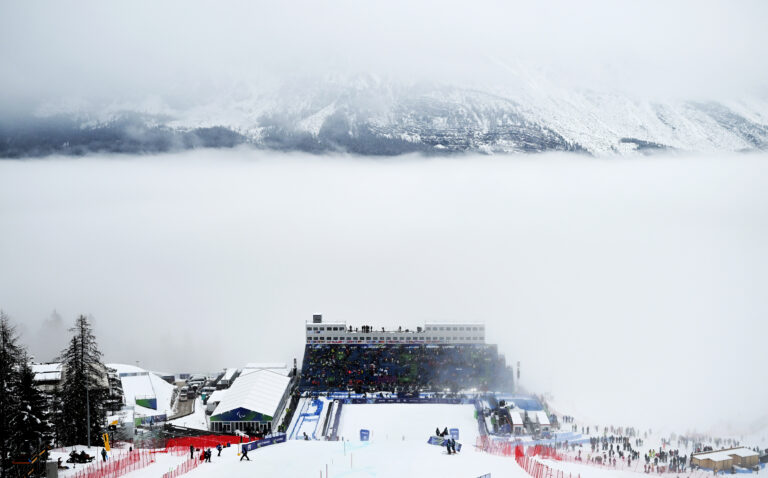 A view down the Slalom course at the Milano Cortina 2026 Paralympic Games. The mountains behind the grand stand are covered in fog.