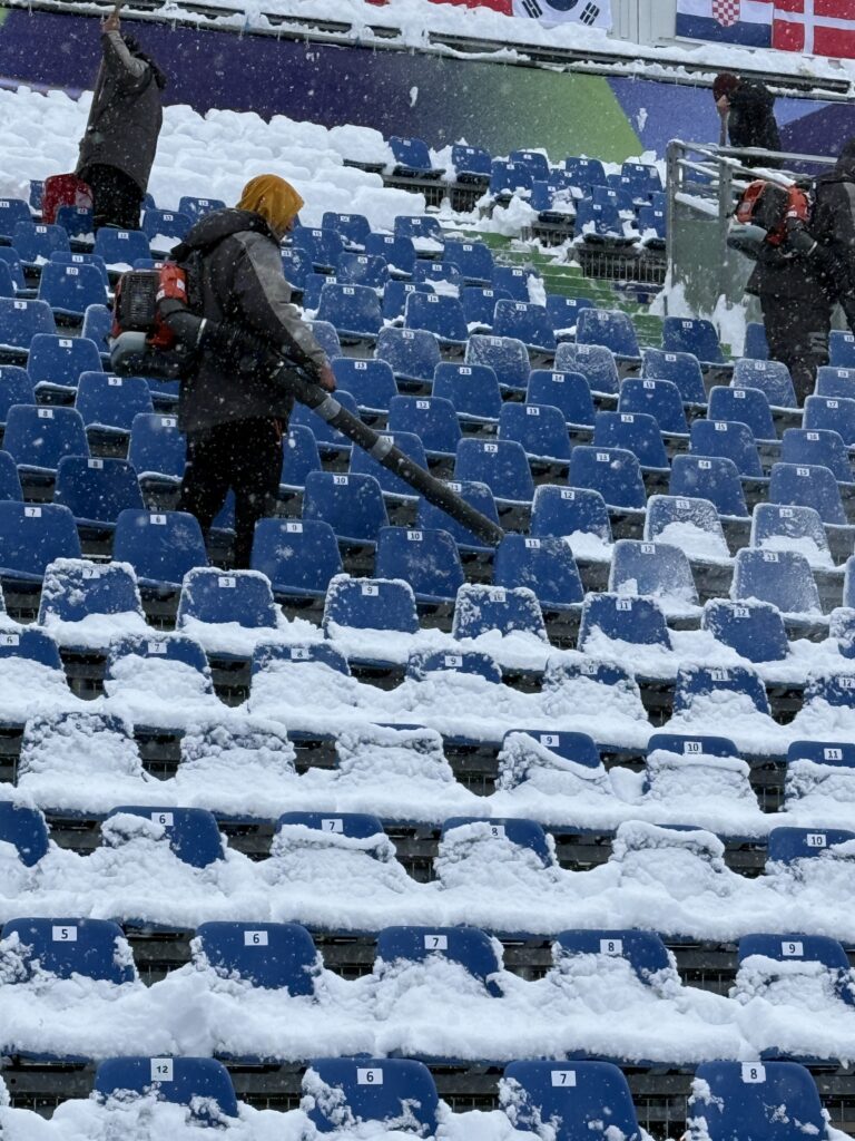 lady holding blowing appliance, blowing snow off seats in a stand