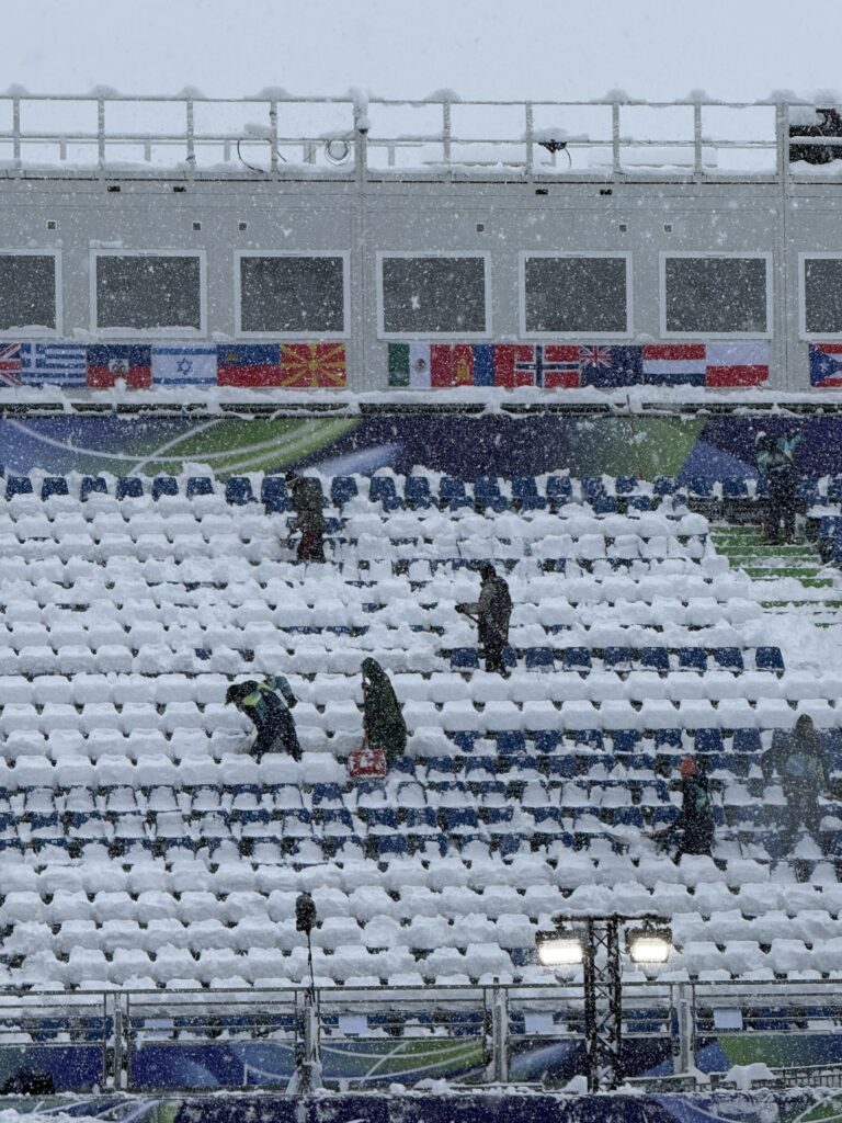 several people blowing snow off seats with a blowing appliance
