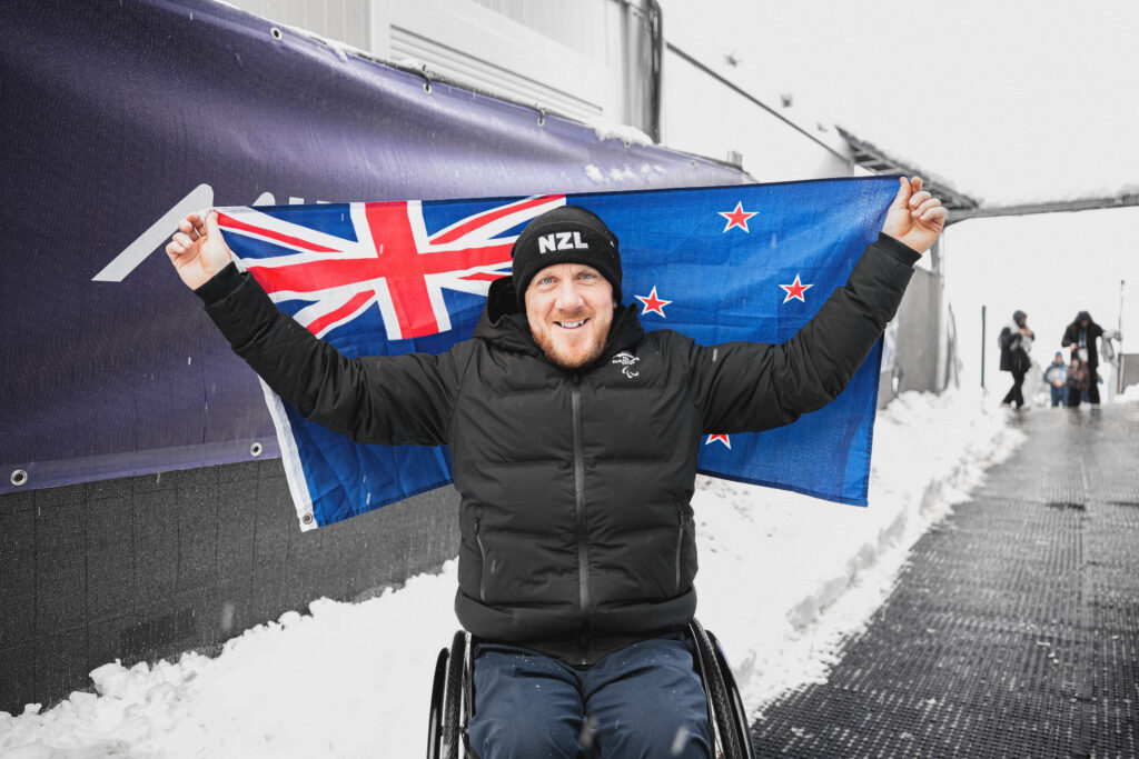 Corey Peters holds the NZ flag at the Milano Cortina 2026 Paralympic Winter Games.