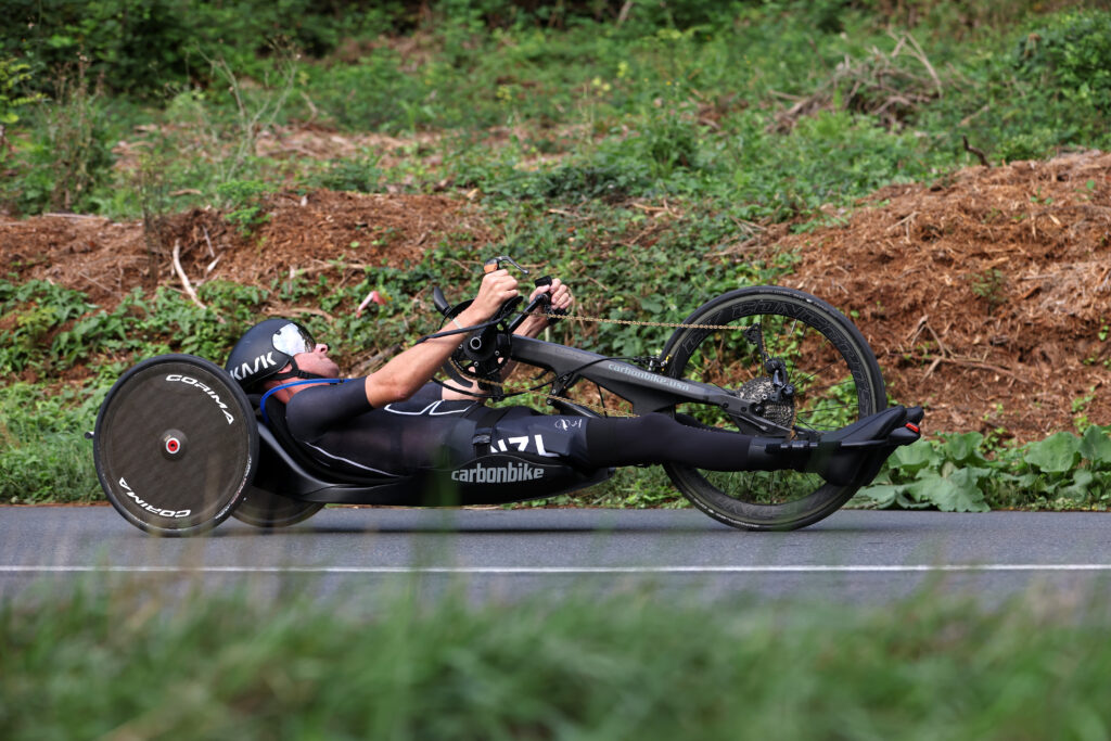Rory Mead pedals his handcycle along a country road at Paris 2024.