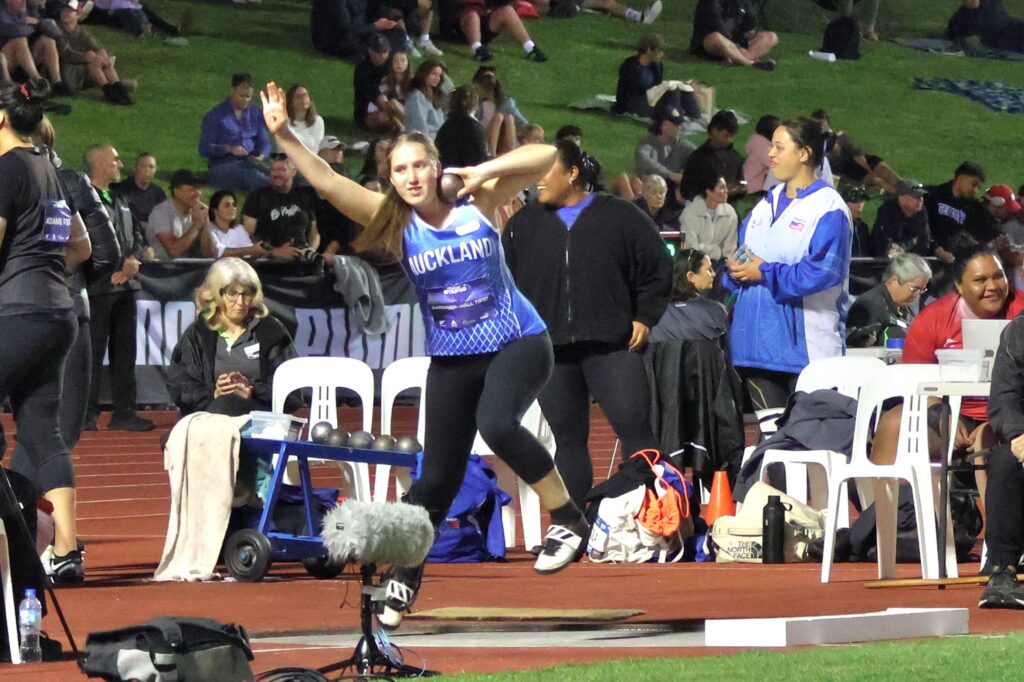 Charli Gardiner-Hall throws a shotput at a competition.