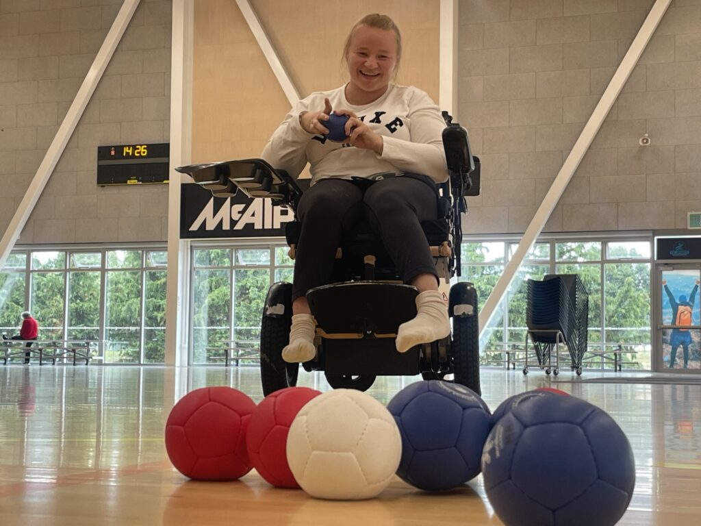 Chloe Sturt sits in a powered wheelchair behind an array of Boccia balls.