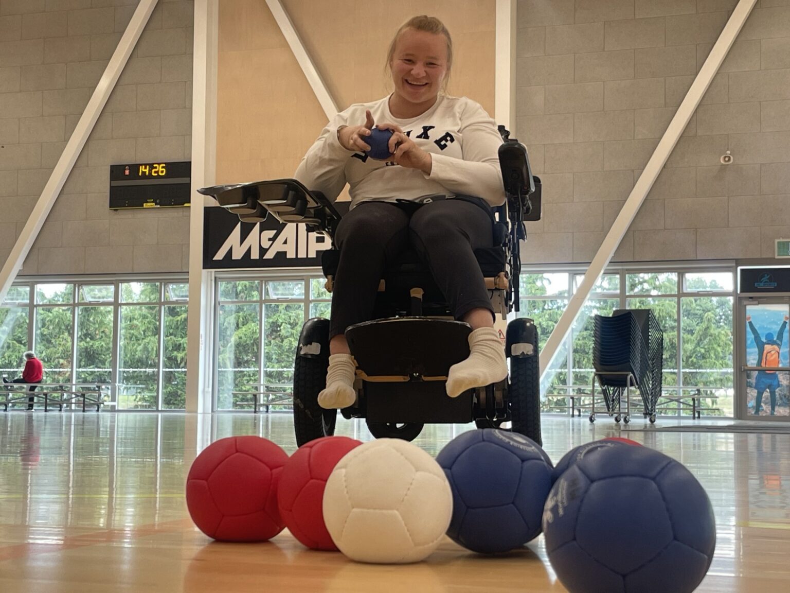 Chloe Sturt sits in a powered wheelchair behind an array of Boccia balls.