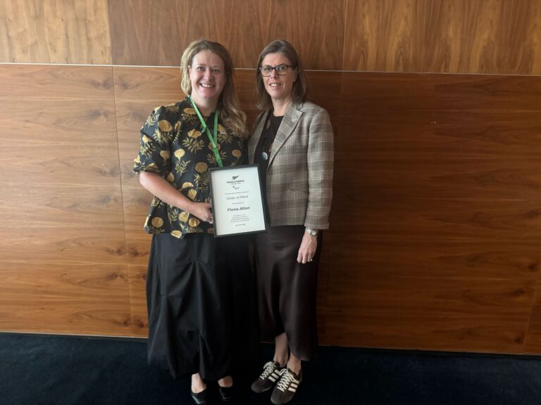 Fiona Allen holds her PNZ Order of Merit alongside PNZ Board member.