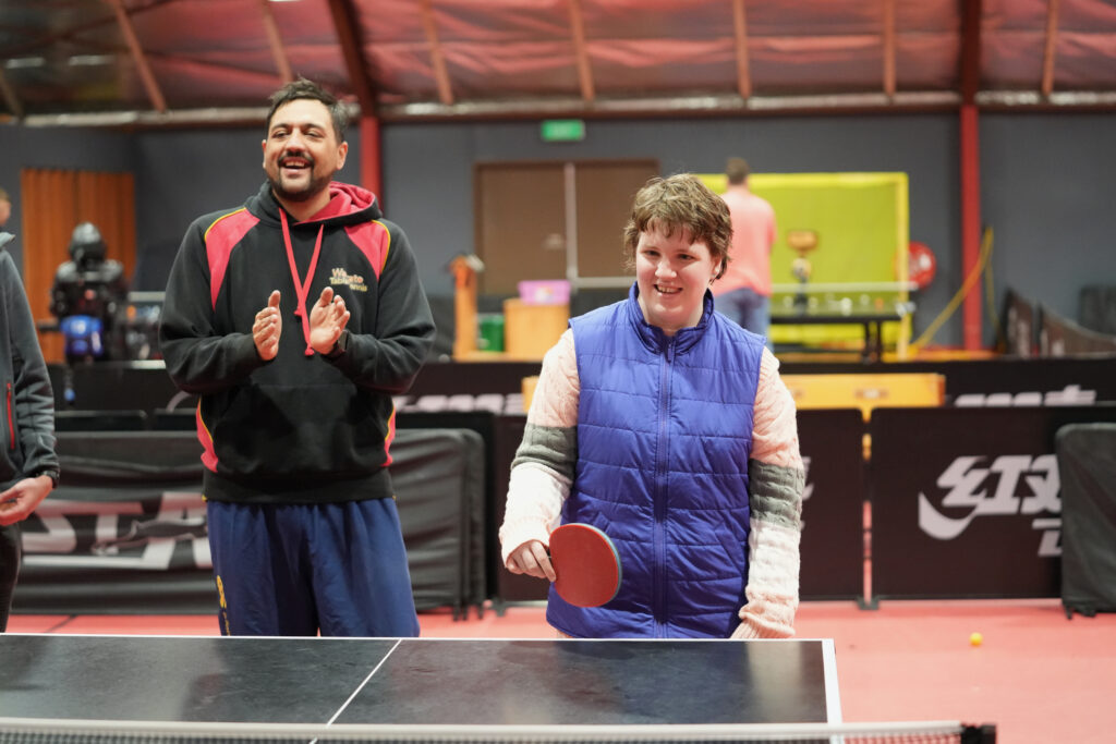 A girl smiles while holding a table tennis bat.