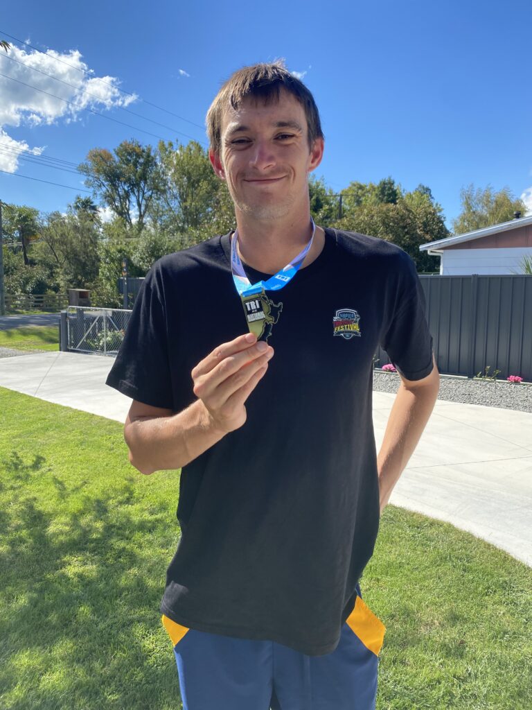 Guy holds a Para triathlon gold medal.