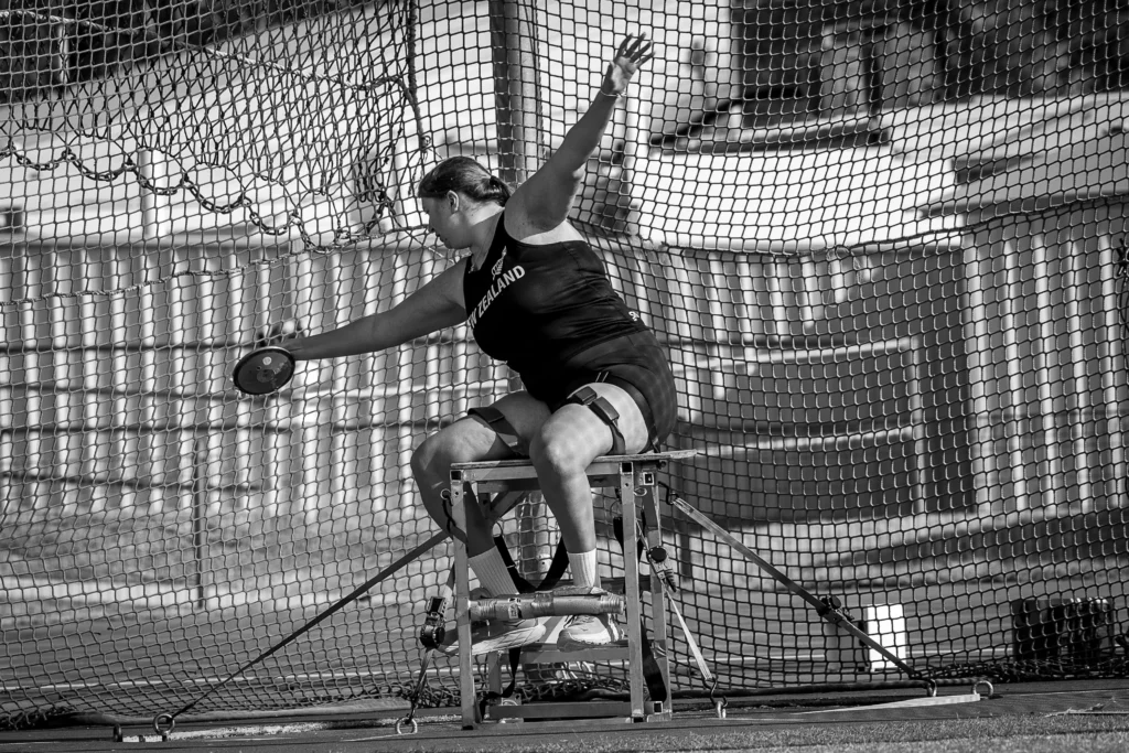 Milly Marshall-Kirkwood extends her arms in preparation to throw a discus from a throwing frame. Credit Jo Harlow.