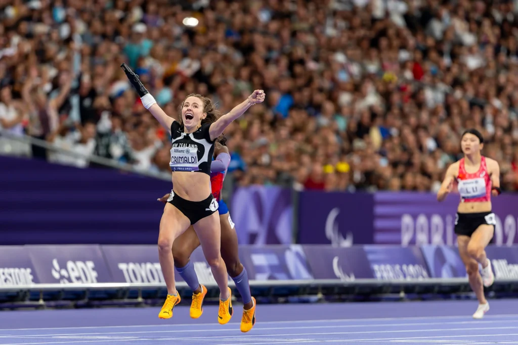 Anna Grimaldi celebrates as she crosses the line in first place at the Paris 2024 Paralympic Games.
