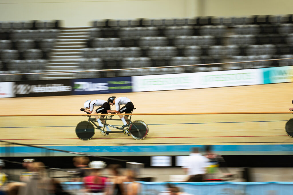 Michael Whittaker photographed cycling the velodrome at speed on the tandem bicycle.