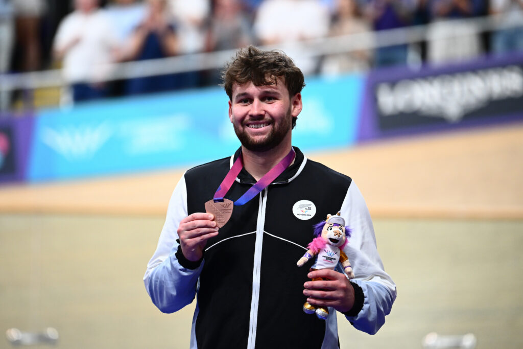 Image of Paralympian #228 Devon Briggs on the podium with a bronze medal at the Glasgow 2026 Commonwealth Games.