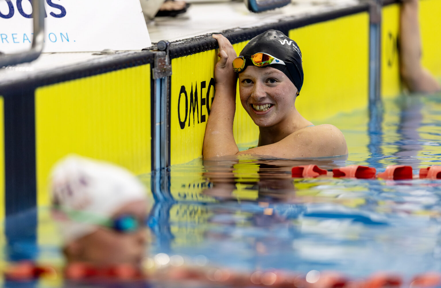 Para swimmer Rylee Sayer pictured holding the side of the pool with a smile on her face at the end of a race at the national open swimming championships.