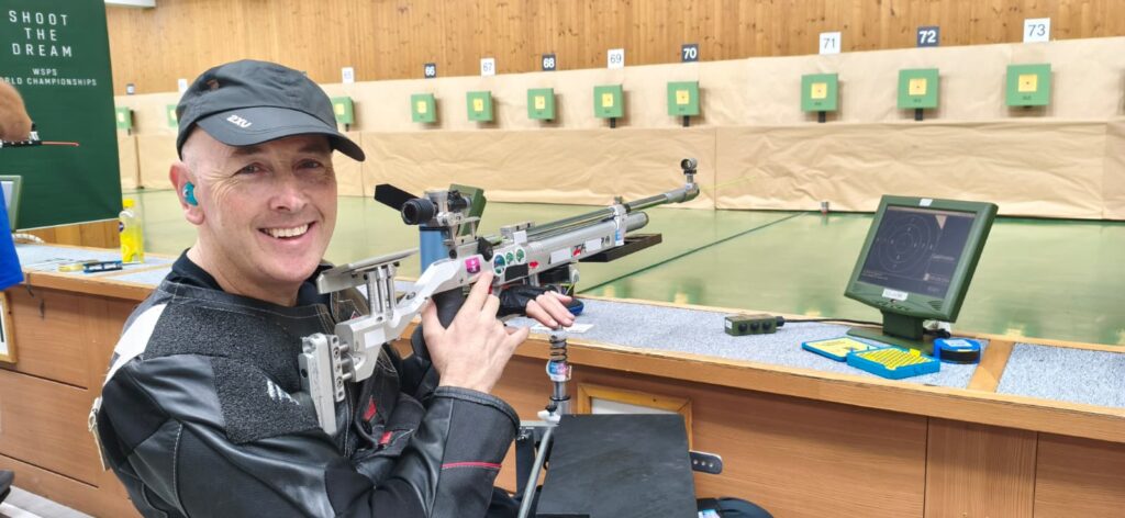 Michael Johnson smiling at camera with his rifle in hand
